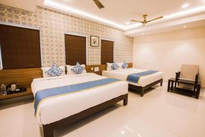 a hotel room with two beds and a chair at SMA Grand inn, Triplicane in Chennai
