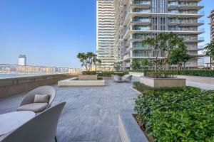 a patio with chairs and tables and a tall building at Luxe Living in Beachfront / 2BR in Dubai Marina in Dubai