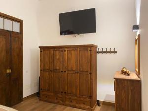 een kamer met een televisie aan de muur en een houten kast bij Casa América in Sabina Alta