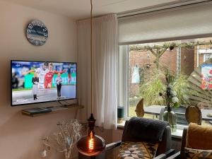 sala de estar con TV y ventana en De Linden, en Egmond aan Zee