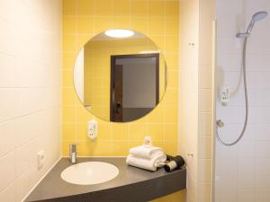 La salle de bains est pourvue d'un lavabo, d'un miroir et d'une douche. dans l'établissement B&B Hotel Kiel-Wissenschaftspark, à Kiel