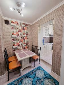 een eetkamer met een tafel en stoelen en een bakstenen muur bij Уютная квартира в хорошем районе Тауке хана in Simkent