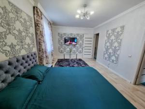 een slaapkamer met een groot bed en een tv aan de muur bij Уютная квартира в хорошем районе Тауке хана in Simkent