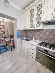 een keuken met witte kasten en een fornuis met oven bij Уютная квартира в хорошем районе Тауке хана in Simkent