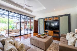 ein Wohnzimmer mit einem Sofa und einem TV in der Unterkunft Tranquility Manor Bali in Sanur