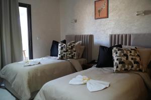 two beds in a hotel room with towels on them at Le Rocher De L'Atlas in Azrou