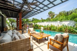 eine Außenterrasse mit einem Tisch, Stühlen und einem Pool in der Unterkunft Tranquility Manor Bali in Sanur