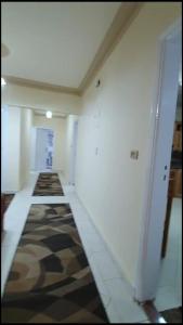 un pasillo con una habitación con paredes blancas y una alfombra en شقة مفروشة فاخرة بأرقى مواقع المنصورة en Mît Khamîs