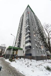 un edificio de apartamentos alto con nieve en el suelo en Квартира студия 1 комнатная на Теремках низкий этаж, en Kiev