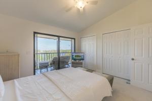 a bedroom with a white bed and a balcony at LAKE PALMS 1 in Sanibel