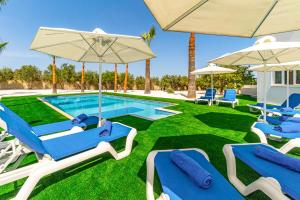 - une piscine avec des chaises et des parasols bleus dans l'établissement Varvara's Villa, à Ayia Napa