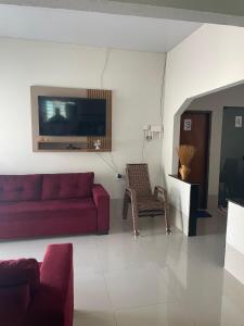 uma sala de estar com um sofá vermelho e uma cadeira em Pousada Ambiente Familiar em Ponte Alta do Tocantins