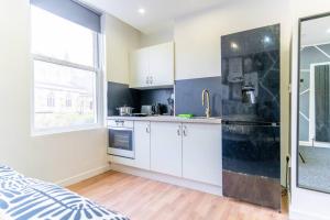 a kitchen with white cabinets and a black refrigerator at Charming Studio Haven in Birmingham