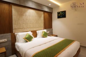 Un dormitorio con una cama grande con almohadas verdes y blancas en LUXIE INN MALABAR, en Perintalmanna