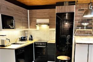 a kitchen with black appliances and a brick wall at Riverside Loft With Sauna in Turku