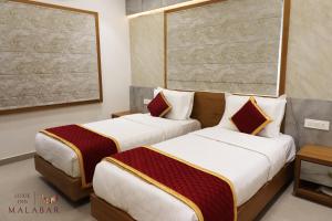 2 łóżka w pokoju hotelowym w obiekcie LUXIE INN MALABAR w mieście Perintalmanna