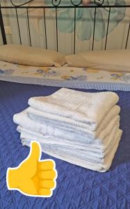 een stapel handdoeken op een bed met een rubberen handschoen bij Casa Mon Amour Livorno in Livorno