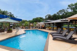 a large swimming pool with lounge chairs in a resort at Pousada Dona Carmita in Brumadinho
