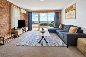 a living room with a blue couch and a brick wall at Bicheno Spa Villa in Bicheno