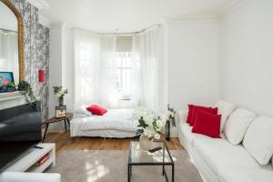 a white living room with a white couch and red pillows at Marvellous Flat in Earls Court in London