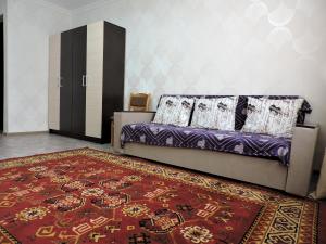 salon z fioletową kanapą i czerwonym dywanem w obiekcie NBG Flat w mieście Ałma-Ata