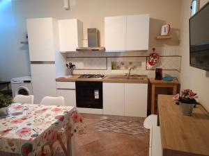 uma cozinha com armários brancos, uma mesa e um lavatório em Per chi ama mare e montagna! em Camaiore