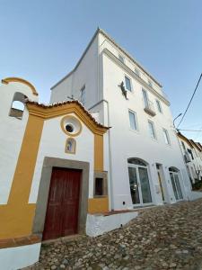 a white building with a red door on a street at Casa Alta T0 in Castelo de Vide