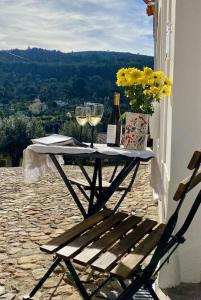 a table with two wine glasses and a vase with flowers at Casa Alta T0 in Castelo de Vide