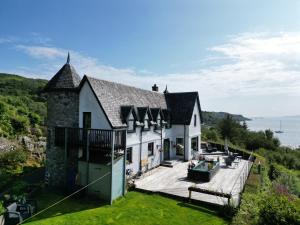a large white house with a deck and the ocean at Corrie House in Craobh Haven