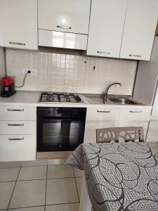 uma cozinha com armários brancos, um fogão e um lavatório em b&b Sirianni em SantʼEufemia Lamezia