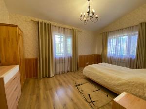 een slaapkamer met een bed, 2 ramen en een kroonluchter bij Turgen house in Taūtürgen