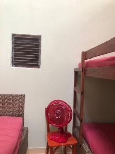 - un ventilateur rouge assis sur un tabouret à côté d'un lit superposé dans l'établissement Casa em Ilha da Crôa - AL, à Barra de Santo Antônio