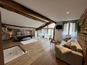 ein großes Wohnzimmer mit einem Sofa und einer Badewanne in der Unterkunft Les Bruyeres Chambres dhotes et Gite in Verteuil-sur-Charente