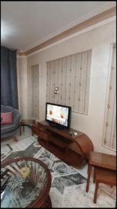 un soggiorno con TV e divano di شقة مفروشة مميزة جدا a Mît Khamîs