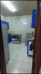 una cucina con armadi blu e pavimento piastrellato bianco di شقة مفروشة مميزة جدا a Mît Khamîs