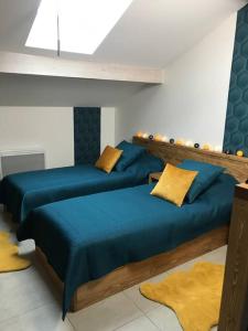 2 Betten in einem Zimmer mit blauer Bettwäsche und gelben Kissen in der Unterkunft M48 *Marquer* T2 atypique Cranves-Sales in Cranves-Sales