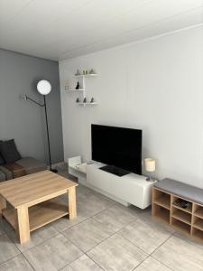 a living room with a flat screen tv on a white cabinet at Chalet nature proche plage in La Ciotat