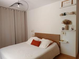 Schlafzimmer mit einem Bett mit weißer Bettwäsche und roten Kissen in der Unterkunft Villa aiguës marines in Pérols