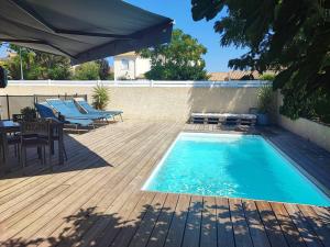 einen Pool mit Stühlen, einem Tisch und einem Sonnenschirm in der Unterkunft Villa aiguës marines in Pérols
