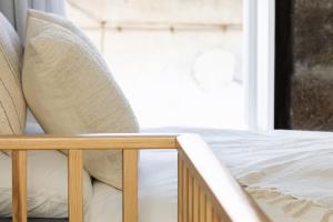 Cama con sábanas blancas y almohadas junto a una ventana en Fisherhouse23, en Câmara de Lobos