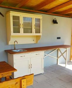 a kitchen with white cabinets and a sink and a table at Zlatý apartmán v soukromí Malá Skála Český Ráj in Koberovy