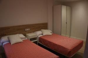 una piccola camera con due letti e un armadio di APARTAMENTOS PICOS DE EUROPA a Santander