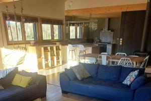 a living room with a blue couch and a kitchen at Maison - Les Loges de St-Claude in Saint-Claude