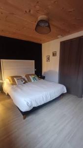 - une chambre avec un lit blanc et un plafond en bois dans l'établissement Maison - Les Loges de St-Claude, à Saint-Claude
