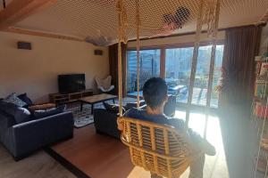 a boy sitting in a chair in a living room at Maison - Les Loges de St-Claude in Saint-Claude
