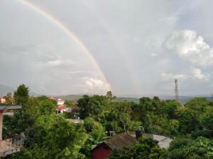 un arco iris sobre una ciudad con árboles y casas en Snow Biscuit Villa en Dharamshala