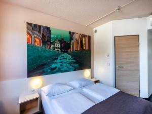 a bedroom with a bed with a large painting on the wall at B&B Hotel Freiburg-Nord in Freiburg im Breisgau