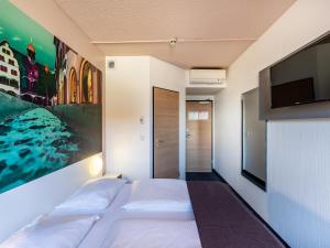 a bedroom with a bed and a flat screen tv at B&B Hotel Freiburg-Nord in Freiburg im Breisgau
