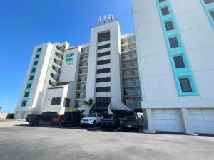 a large white building with cars parked in a parking lot at Condo on the Beach- walk to restaurants, shops and activities. in Gulf Shores