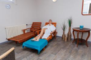 a man sitting in a chair with his foot on a ottoman at Hotel FIT in Přerov
